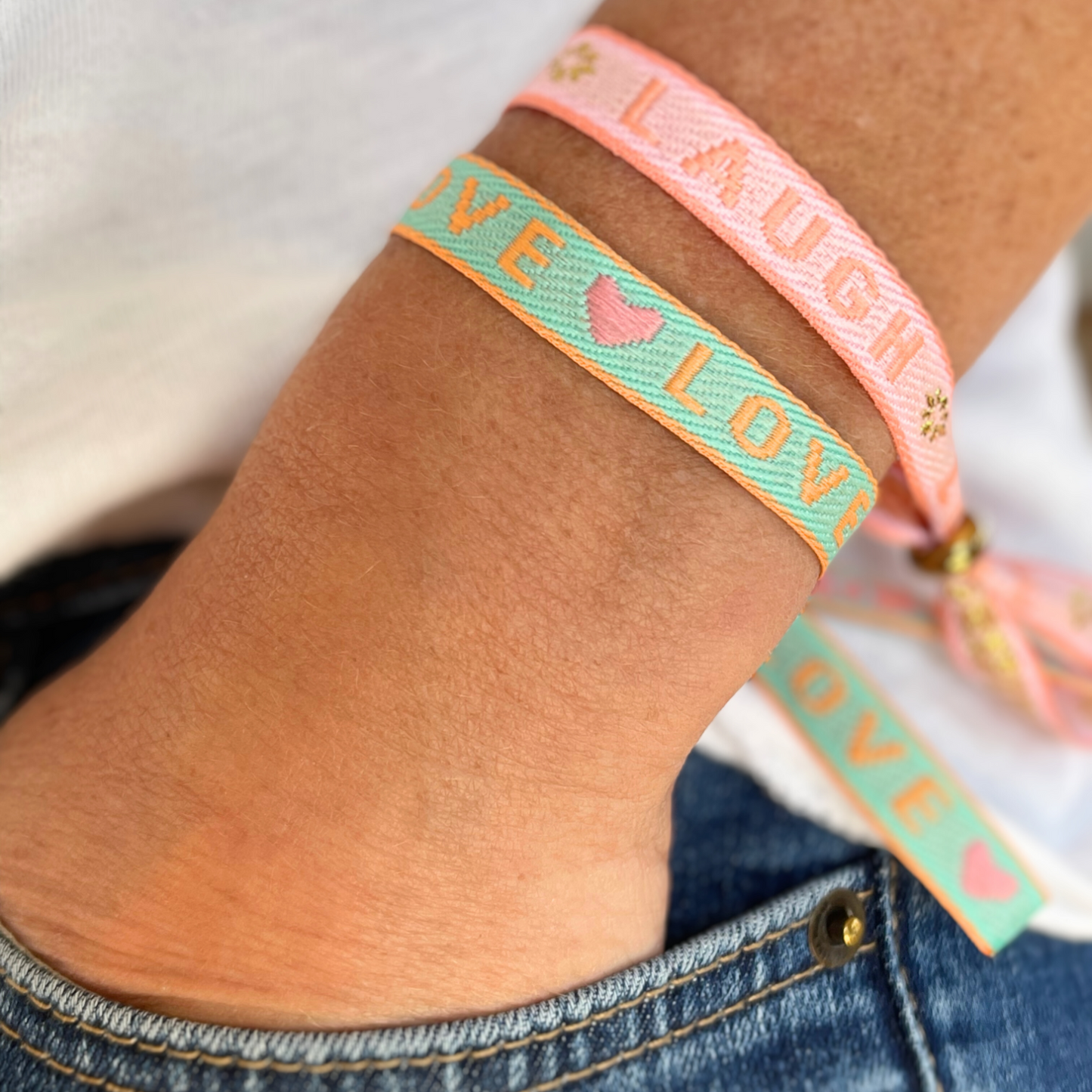 Statement Armband mit "Live Laugh Love" am Arm einer Frau.