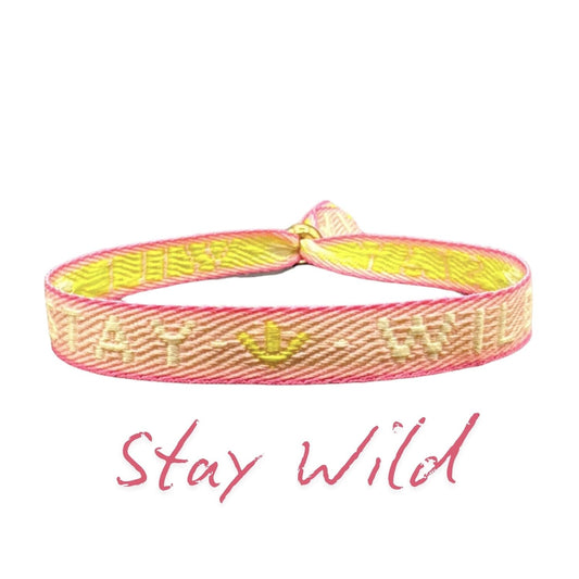 Statement-Armband – Stay Wild, rosa Stoffarmband mit verstellbarem Schieber und gelbem Text.