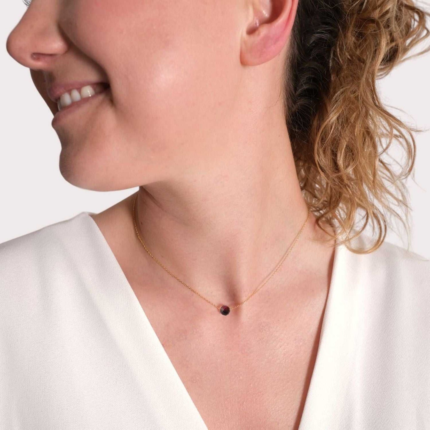 Frau trägt vergoldete Silberkette mit tiefrotem Granat als Geburtsstein Kette Januar für Steinbock, symbolisiert Beständigkeit und innere Stärke.
