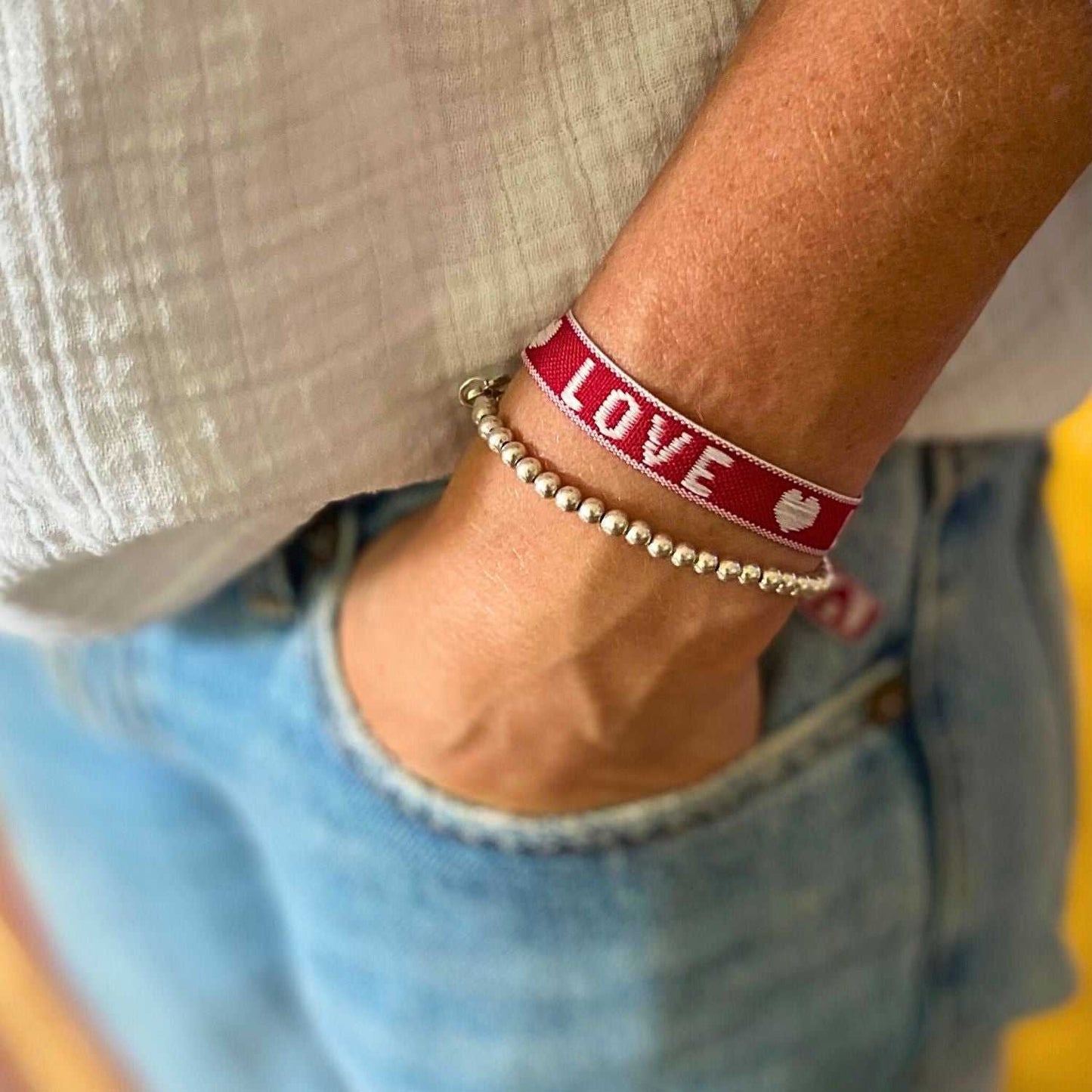 Boho Armbänder Set mit rotem Love-Statement-Armband und Glasperlenarmbändern am Handgelenk.