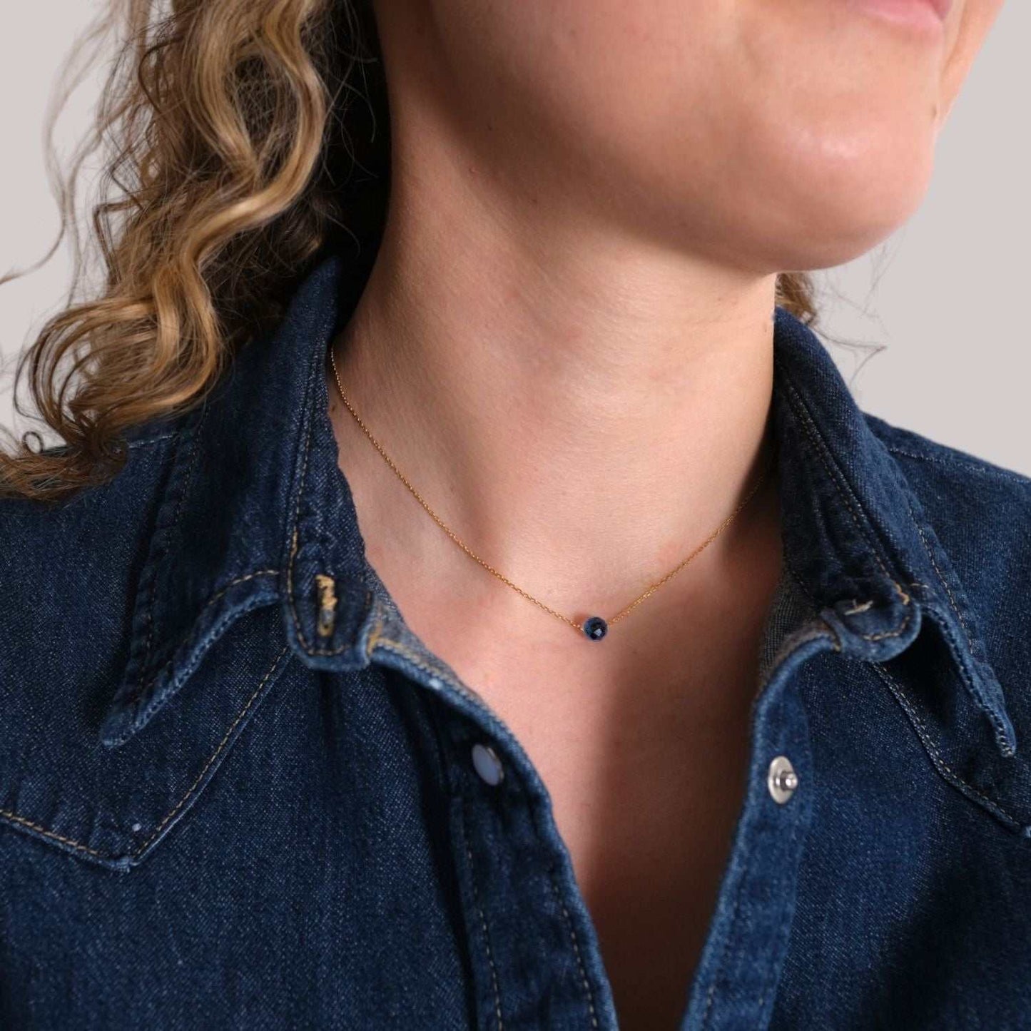 Geburtssteinkette mit Saphir-Geburtsstein für Jungfrau, getragen von Frau, symbolisiert Weisheit und innere Stärke.