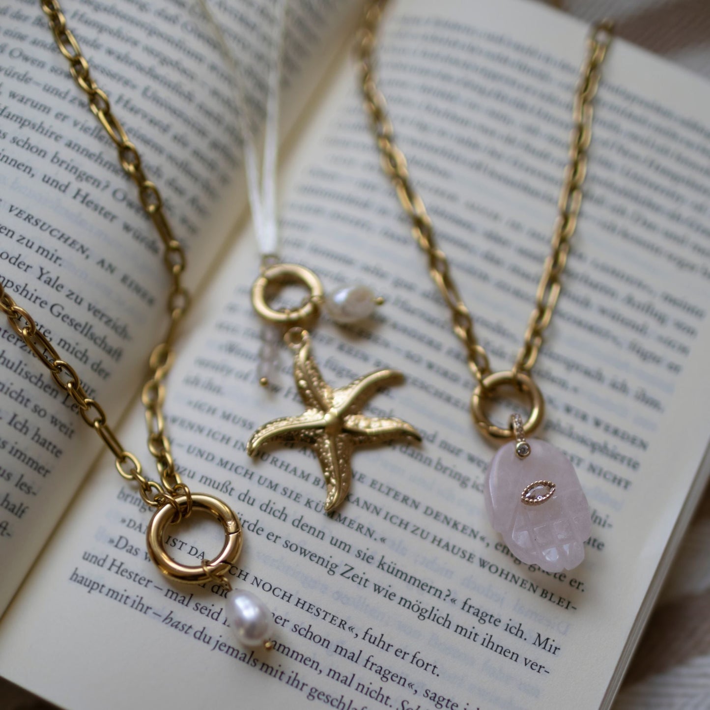 Vergoldete Gold Kette mit Rosenquarz Anhänger, individuell anpassbar, auf offenem Buch.