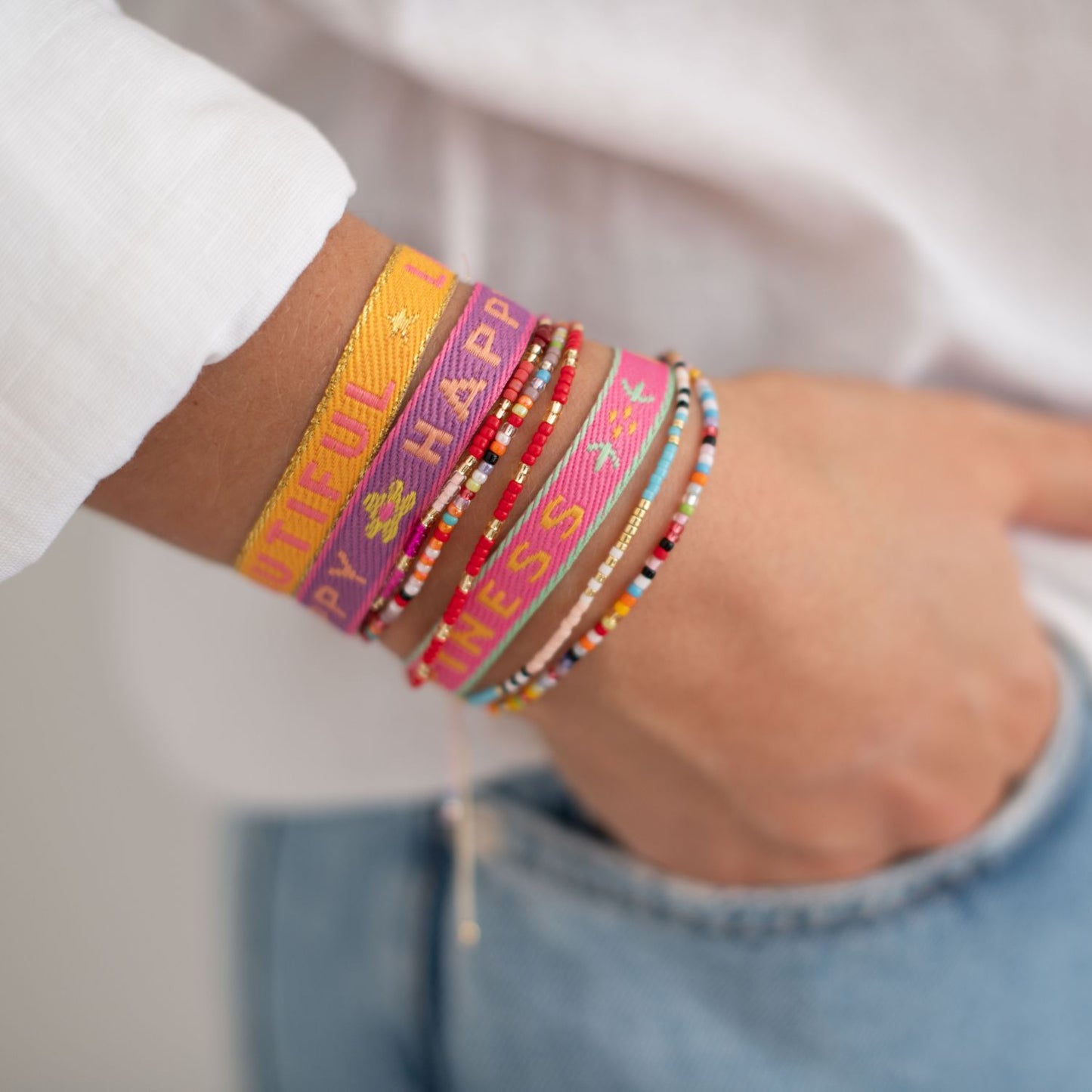 verschiedene bunte stoff- und perlenarmbänder am arm einer frau