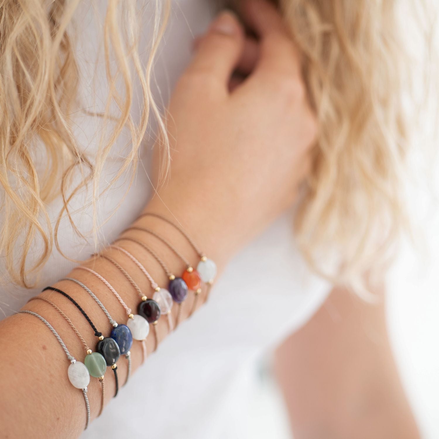 Freundschaftsarmband mit Mondstein und weiteren Edelsteinarmbändern am Arm einer Frau